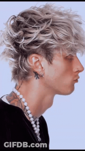 A Man With A Tattoo On His Neck Wearing Pearls And Earrings GIF