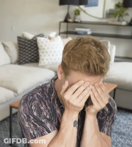 A Man With A Tattoo On His Wrist Is Covering His Face GIF