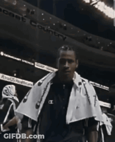 A Man With A Towel Around His Neck Is Standing In Front Of A Sign That Says " Peace Country " GIF