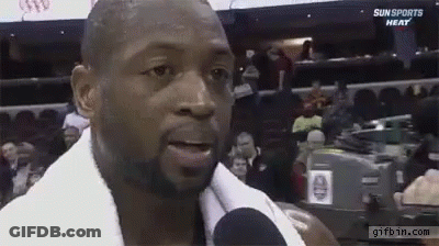 A Man With A Towel Around His Neck Is Talking Into A Microphone At A Sun Sports Heat Game . GIF