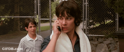 A Man With A Towel Around His Neck Is Talking On His Cell Phone GIF