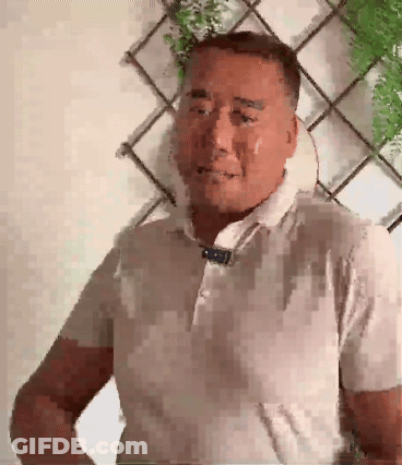 A Man With A Towel Around His Neck Looks At The Camera GIF