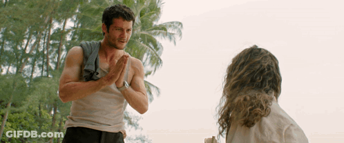 A Man With A Towel Around His Shoulder Talks To A Woman GIF