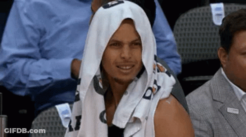 A Man With A Towel Wrapped Around His Head Is Sitting In The Stands At A Basketball Game . GIF