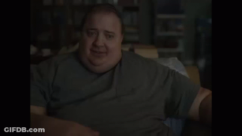 A Man With A Very Large Belly Is Sitting At A Table And Smiling . GIF