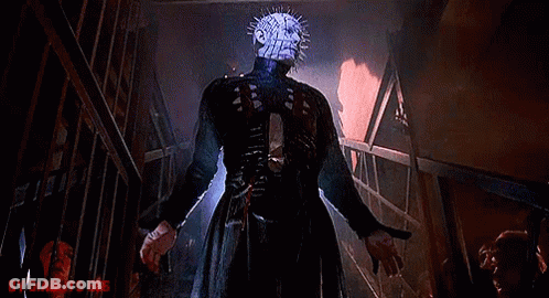 A Man With A Very Spiky Head Is Standing In A Dark Room Holding A Knife . GIF