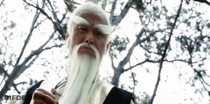 A Man With A White Beard And Mustache Is Standing In Front Of A Tree . GIF