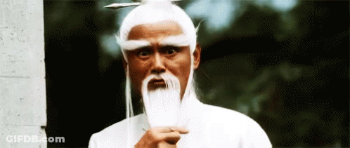 A Man With A White Wig And A Long Beard Is Holding A Sword . GIF