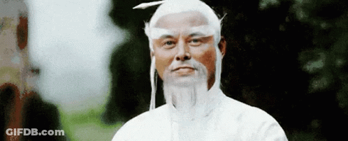A Man With A White Wig And Beard Is Standing In Front Of A Forest . GIF