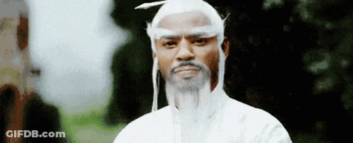 A Man With A White Wig And Beard Is Standing In Front Of Trees . GIF