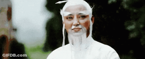 A Man With A White Wig And Beard Is Wearing A White Robe . GIF