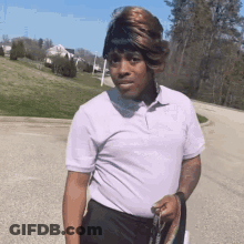 A Man With A Wig On His Head Is Walking Down A Street GIF