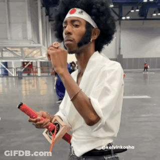 A Man With An Afro Wearing A Headband With A Red And White Circle On It GIF