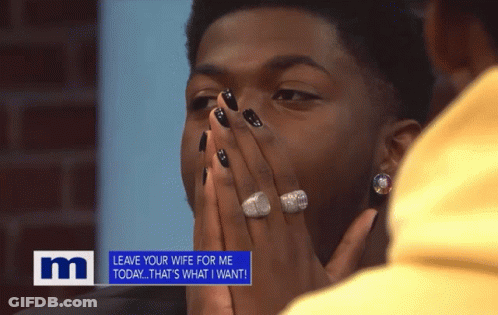A Man With Black Nails And A Ring On His Finger Is Covering His Face In Front Of A M Sign GIF
