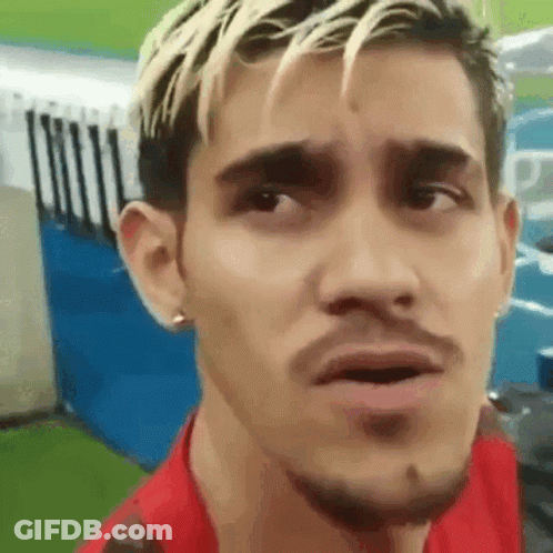 A Man With Blonde Hair And A Beard Is Making A Funny Face While Wearing A Red Shirt . GIF