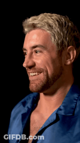 A Man With Blonde Hair And A Beard Is Smiling And Wearing A Blue Shirt GIF