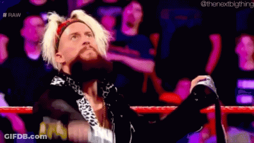 A Man With Blonde Hair And A Beard Is Standing In A Wrestling Ring With His Hands In The Air . GIF
