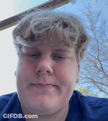 A Man With Blonde Hair And A Blue Shirt Is Smiling GIF