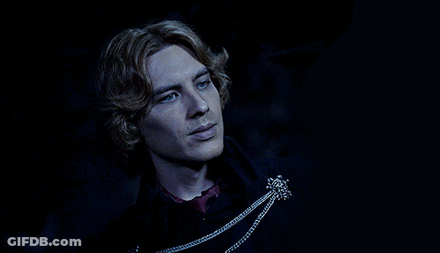 A Man With Blonde Hair And Blue Eyes Is Wearing A Black Coat GIF
