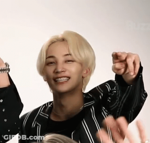 A Man With Blonde Hair And Braces Is Pointing At The Camera . GIF