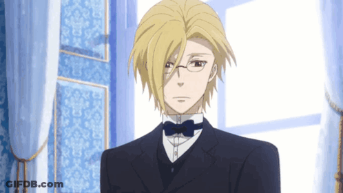 A Man With Blonde Hair And Glasses Is Wearing A Suit And Bow Tie GIF