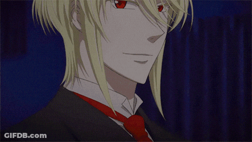 A Man With Blonde Hair And Red Eyes Is Wearing A Black Suit And Tie GIF