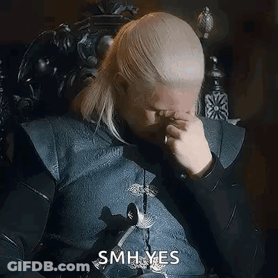 A Man With Blonde Hair Is Sitting In A Chair And Rubbing His Eyes . GIF