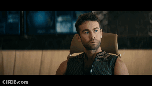 A Man With Blonde Hair Is Sitting In Front Of A Large Window GIF