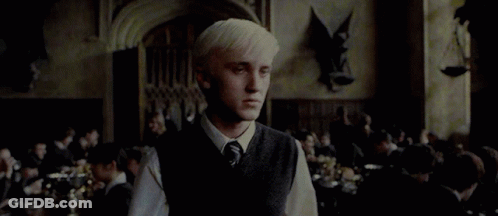 A Man With Blonde Hair Is Standing In A Room With A Crowd Of People . GIF