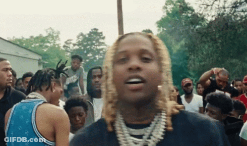 A Man With Blonde Hair Is Standing In Front Of A Crowd Of Men . GIF