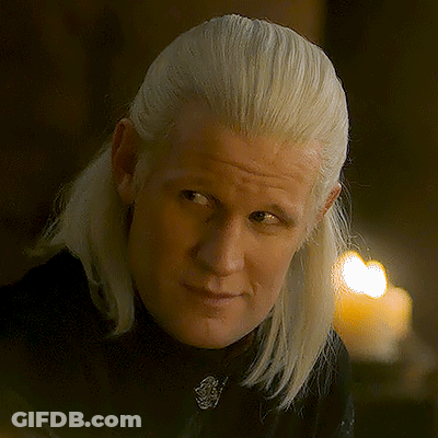 A Man With Blonde Hair Is Wearing A Black Shirt And Looking At The Camera GIF