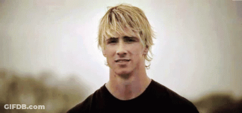A Man With Blonde Hair Is Wearing A Black Shirt And Looking At The Camera GIF