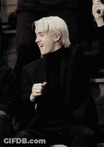 A Man With Blonde Hair Is Wearing A Black Turtleneck And A Black Jacket . GIF