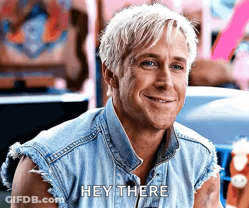 A Man With Blonde Hair Is Wearing A Denim Vest And Smiling While Saying Hey There . GIF