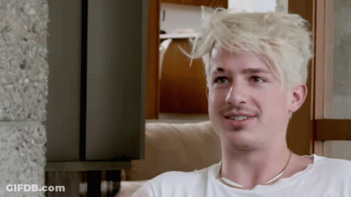 A Man With Blonde Hair Is Wearing A White Shirt And Gold Chain Around His Neck GIF
