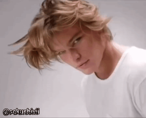 A Man With Blonde Hair Is Wearing A White T-Shirt With The Hashtag @Sekushivii GIF