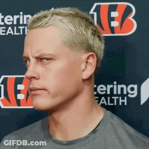 A Man With Blonde Hair Stands In Front Of A Sign That Says Tering Health GIF