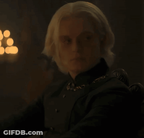 A Man With Blonde Hair Wearing A Black Shirt And A Gold Chain Around His Neck GIF