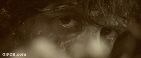 A Man With Blood On His Face Is Holding An Arrow GIF