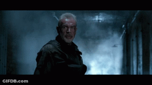 A Man With Blood On His Face Is Standing In A Dark Room GIF