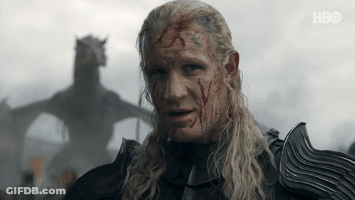 A Man With Blood On His Face Stands In Front Of A Dragon With Hbo Written On The Bottom Right GIF