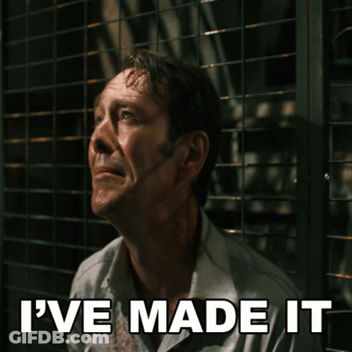 A Man With Blood On His Shirt Is Behind A Fence With The Words I 'Ve Made It Above Him GIF