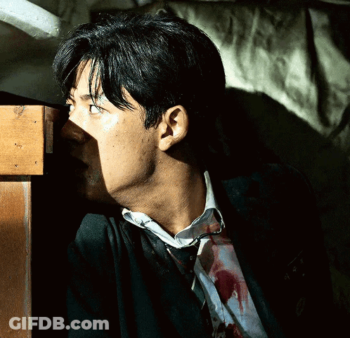 A Man With Blood On His Shirt Is Standing Next To A Table GIF