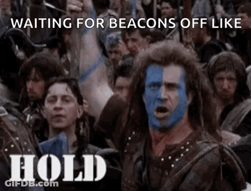 A Man With Blue And White Paint On His Face Is Standing In Front Of A Crowd Of People Holding Up Their Arms . GIF