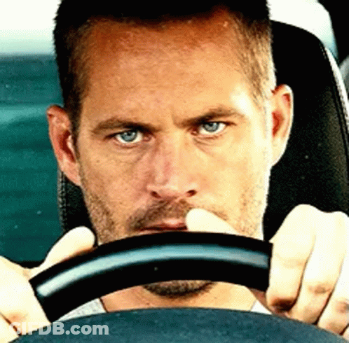 A Man With Blue Eyes Is Holding The Steering Wheel GIF