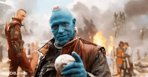 A Man With Blue Hair And A Beard Is Holding A Skull . GIF