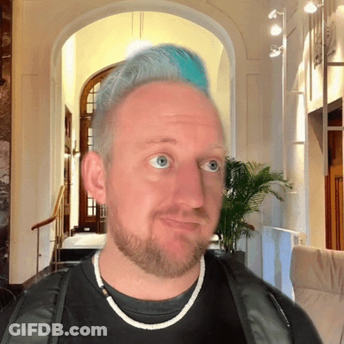 A Man With Blue Hair And A Beard Is Looking At The Camera GIF