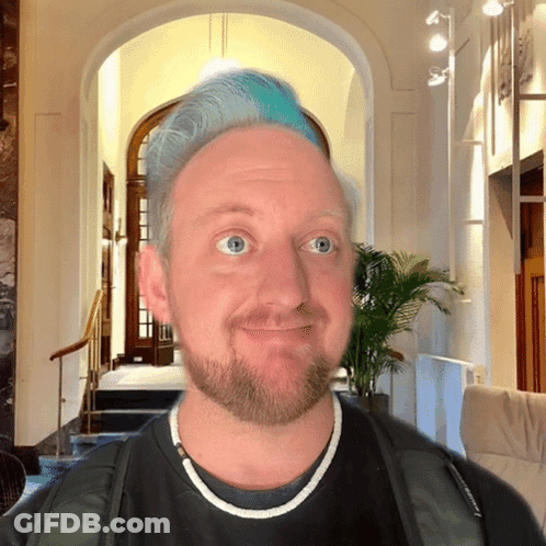 A Man With Blue Hair And A Beard Wears A Black Shirt GIF