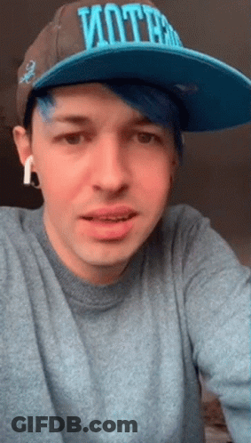 A Man With Blue Hair And A Hat That Says Vote GIF