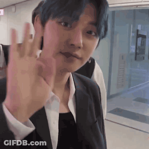 A Man With Blue Hair Is Waving His Hand GIF